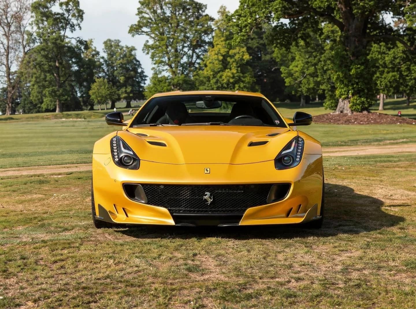 A yellow Ferrari F12tdf on parkland grass